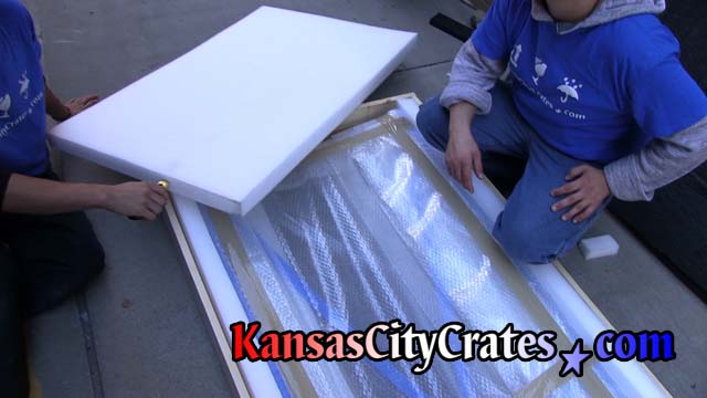 Glass panels wrapped in bubble wrap are packed with foam in commercial crate