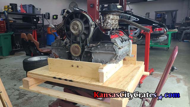Front view of classic car engine bolted to craddle in wood crate