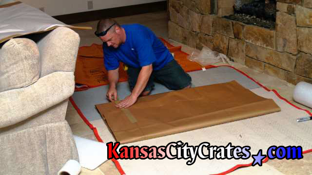 Crater working on blankets covering the floor wrapping lithograph in paper pads.