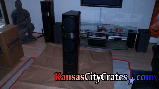 Focal speaker being wrapped in paper while sitting on furniture blanket protecting floor.