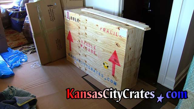 Crate with shock sensor and shipping symbols sit on cardboard to protect the floor