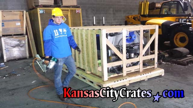 Safety director of Kansas City Crates closes slat crate wearing hard hat, eye protection, steel toe boots and safety glasses