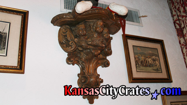 Antique wood Putti pedestal holding collector doll on wall in Kansas City Mansion.