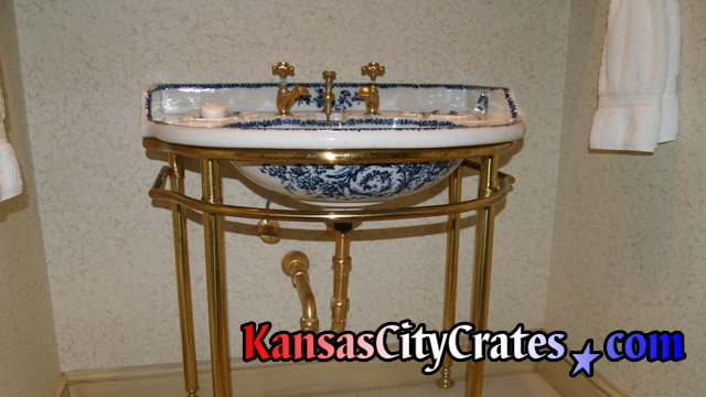 Porcelain lavatory basin with gold fixtures before crating.