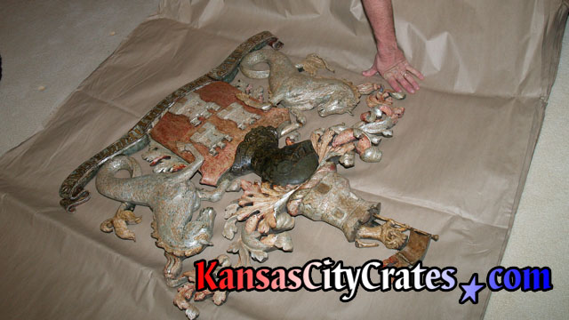 Positioning Antique Wood Coat Of Arms on paper in crate before mounting