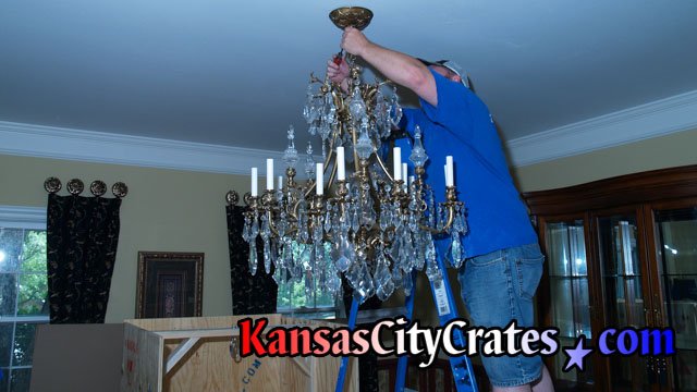 Electrician removing canopy of chandelier to disconnect wiring at home in Leawood KS 66224