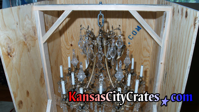 Close up view of heavy chandelier hanging from brace reinforced by internal frame inside export crate.