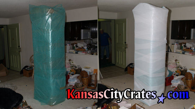 Two views of grandfather clock cabinet wrapped in bubble wrap and stretch wrap for packing into export crate for shipping.