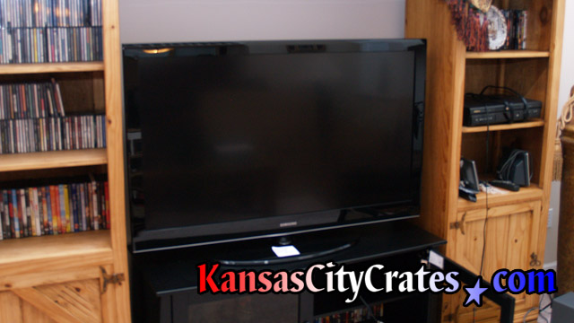 Large flat panel TV sitting in entertainment center before crating.