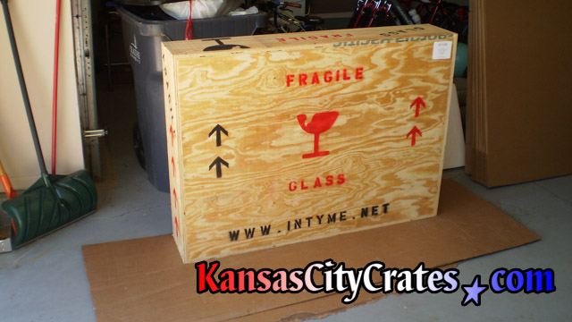 Crate marked for transport staged on carboard for loading by mover.