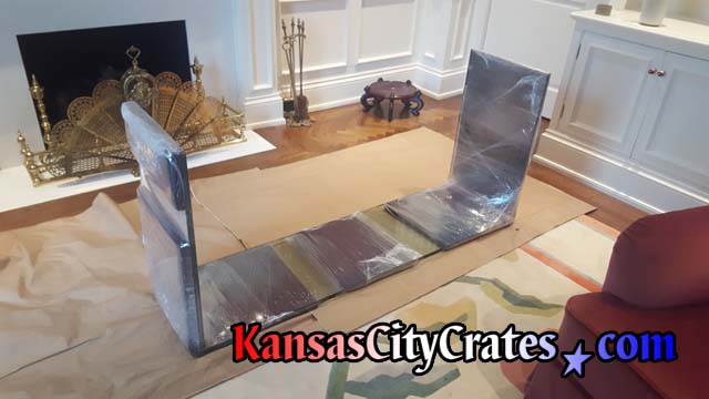 Fragile glass table is protected with foam padding secured by stretch wrap before loading into solid wall furniture crate