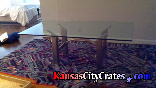 Large heavy dining room glass table top next to solid wall crate for shipping.