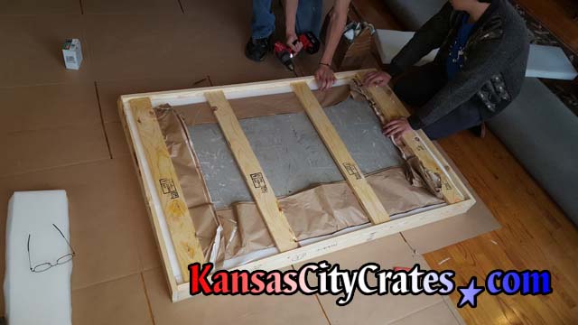 Wood slats are placed inside solid wall crate to hold stone top and shipping foam in place