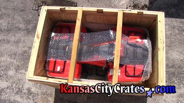 ATV in crate protected by lid supports enabling crates to be stacked during transport