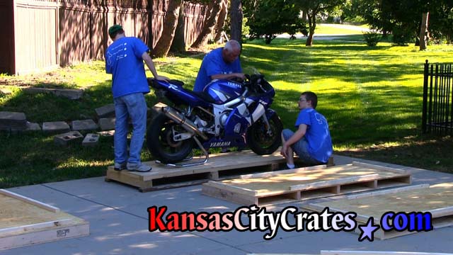 Craters adjust position of sport bike on pallet before attaching crate sides
