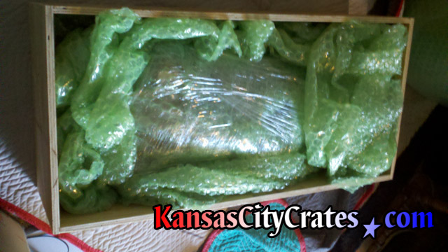 Neon sign bubble wrapped inside vault like wood crate for shipping.
