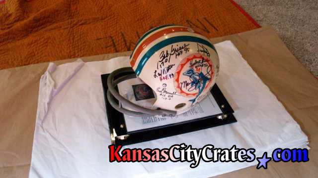 Team autographed helmet on acid free tissue paper for wrapping before packing into wood crate.