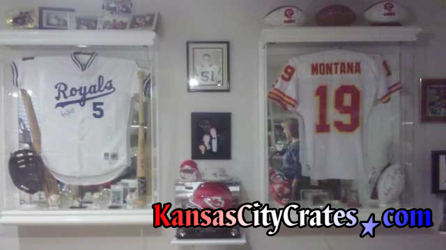 2 Glass cases containing Baseball jersey of George Brett and Football jersey of Joe Montana, both autographed, being packed into wood crate for storage.