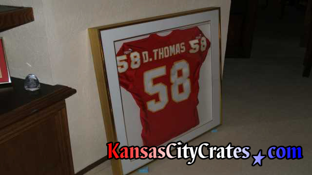 Crating Derrick Thomas football jersey in glass case.