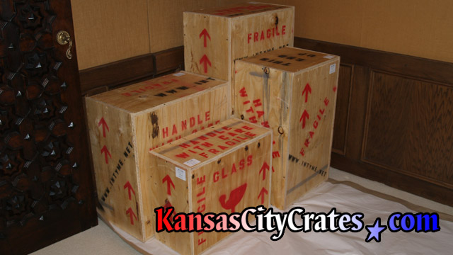 Four wood boxes containing artwork and glassware packed at home in Kansas City for storage.