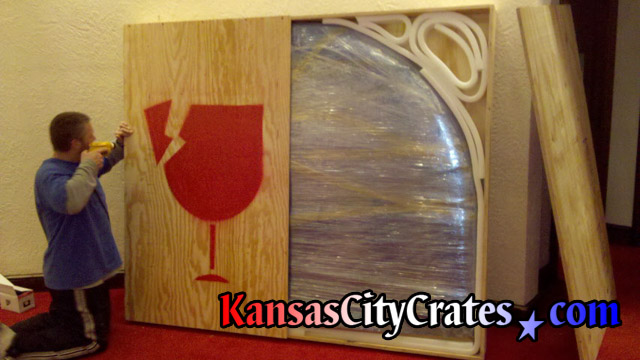 Attaching lid on large wood crate for stained glass window behind bar in suite at Arrowhead Stadium Kansas City MO