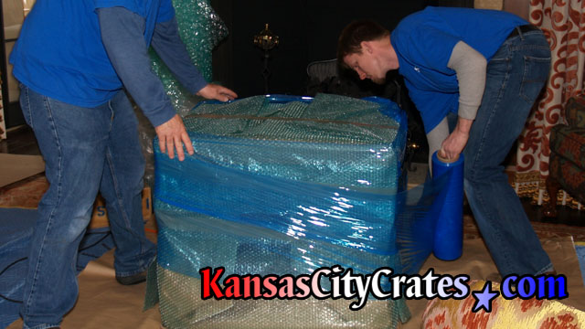 Example photos of different items that have it's paper and bubble wrap packaging secured with plastic stretch wrap to ease handling of object while loading or unloading crate that also provides a moisture barrier.