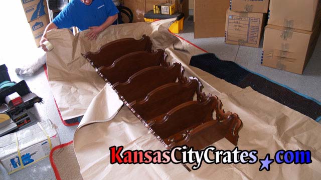 Paper wrapping fine antique corner shelf for packing into wood crate.