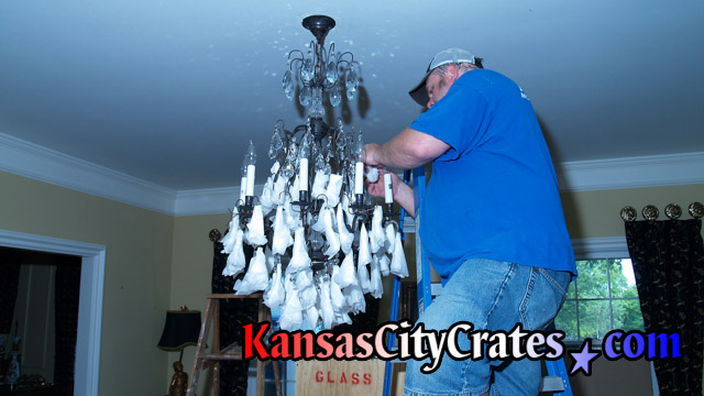 Packing fragile crystals on chandlier before removing from ceiling to hang in crate.